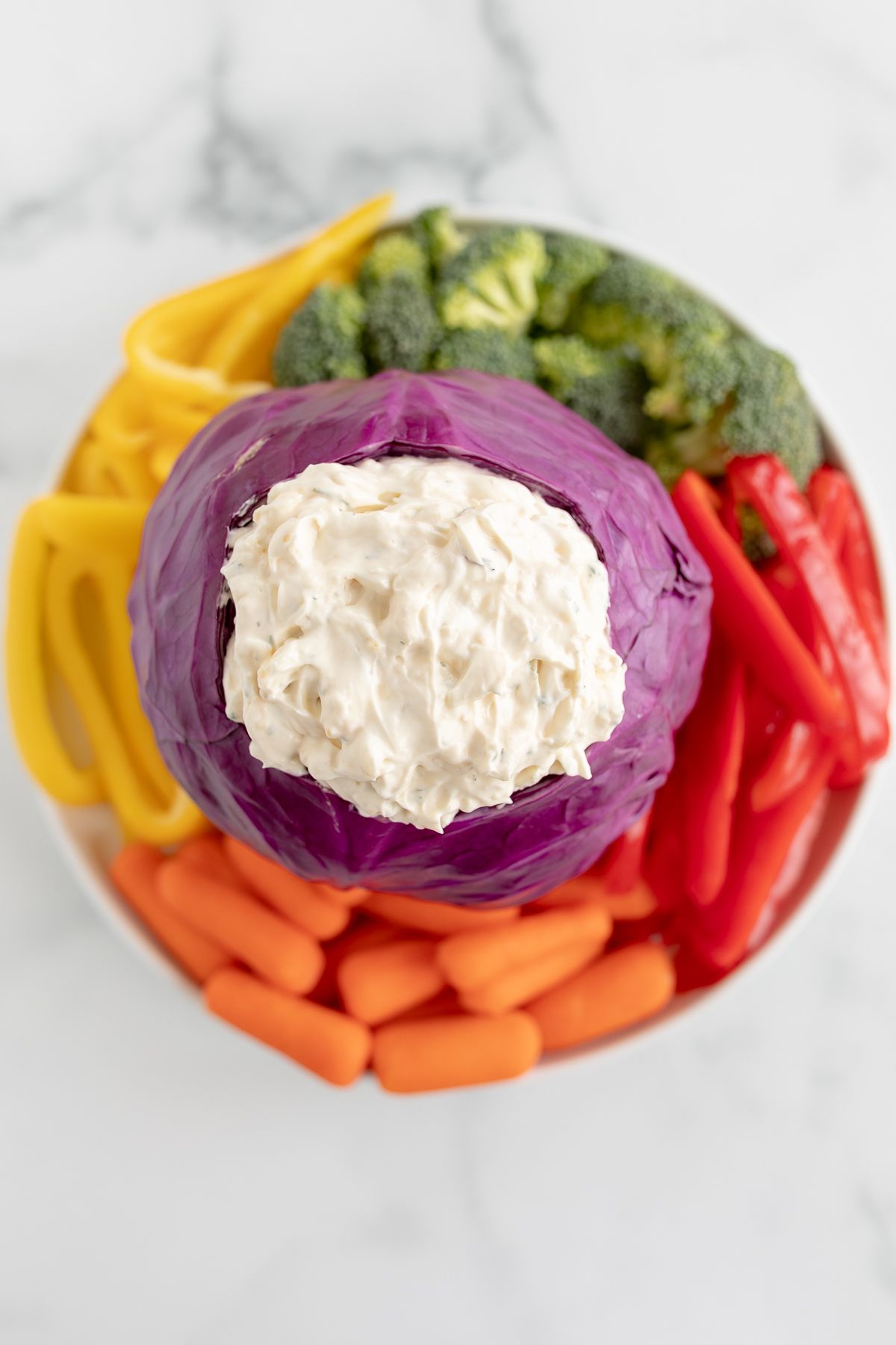 Veggie dip inside a bowl made of purple cabbage