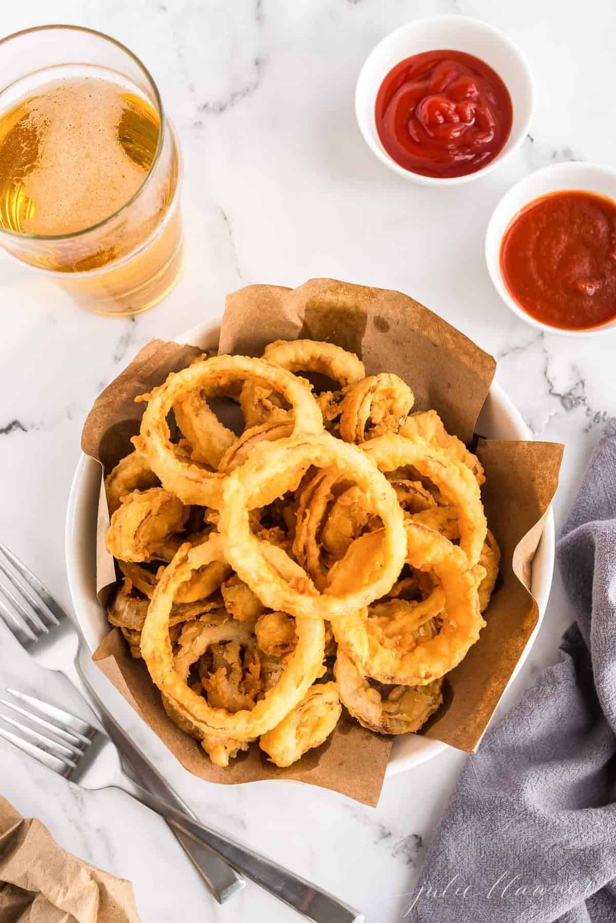 Onion rings in a bowl, with ketchup to the side. 