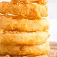 Stack of homemade onion rings on a piece of butcher paper.