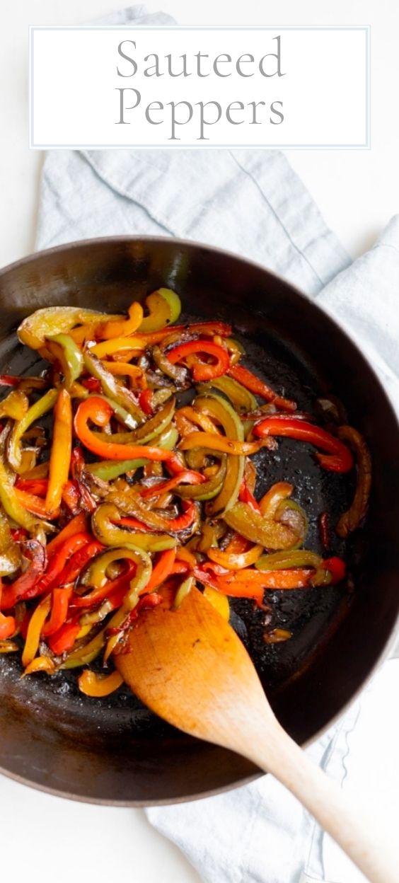 A cast iron pan full of sauteed bell peppers, wooden spoon to the side.