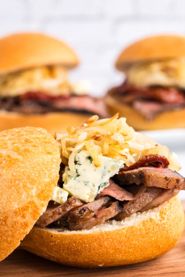 A mouthwatering steak sandwich with tender meat and gooey cheese elegantly served on a rustic wooden board.