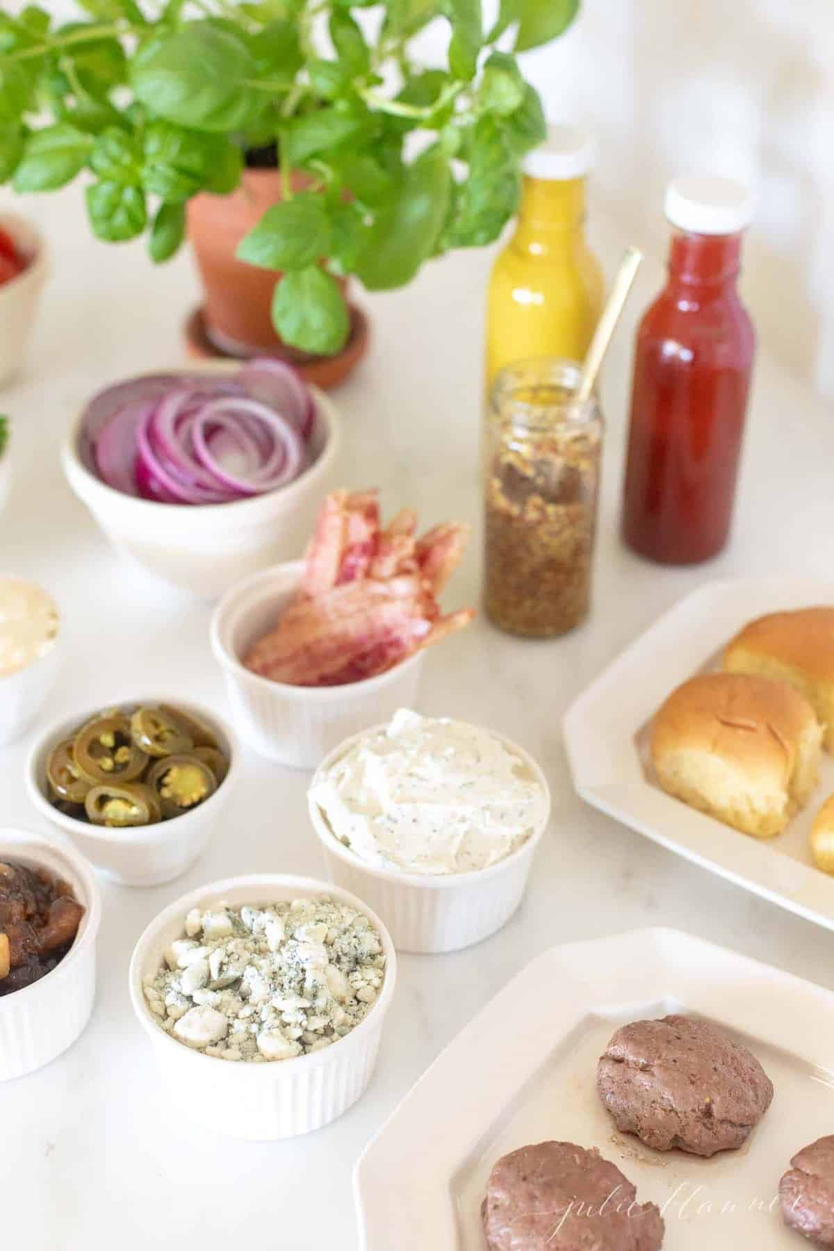 An array of toppings and condiments displayed for a burger bar.