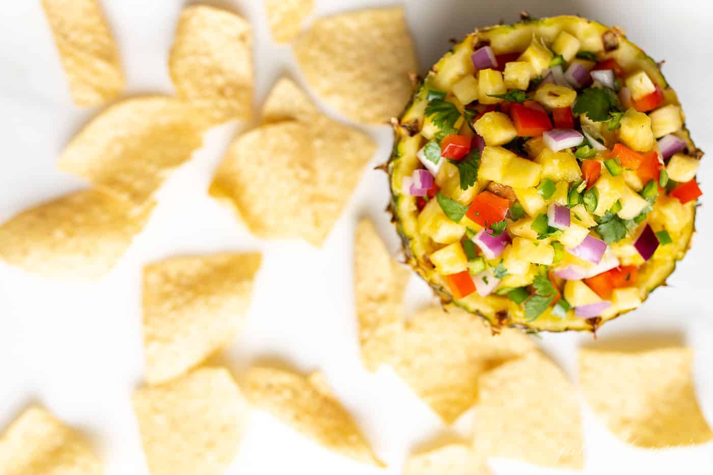 Pineapple salsa in a pineapple bowl, surrounded by tortilla chips.