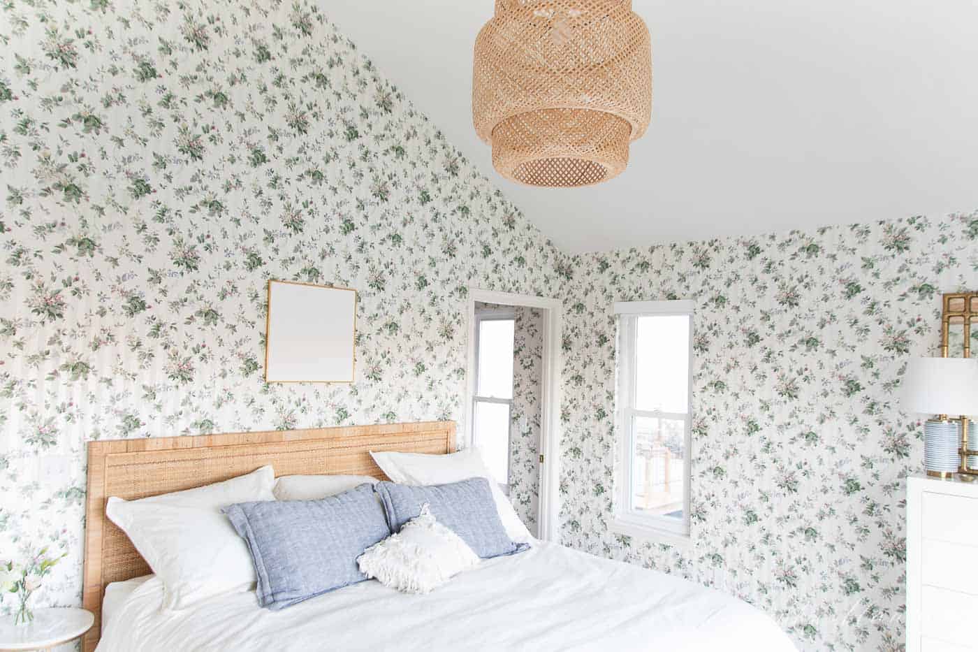 A white bedroom with wooden accents and a statement floral wallpaper. 