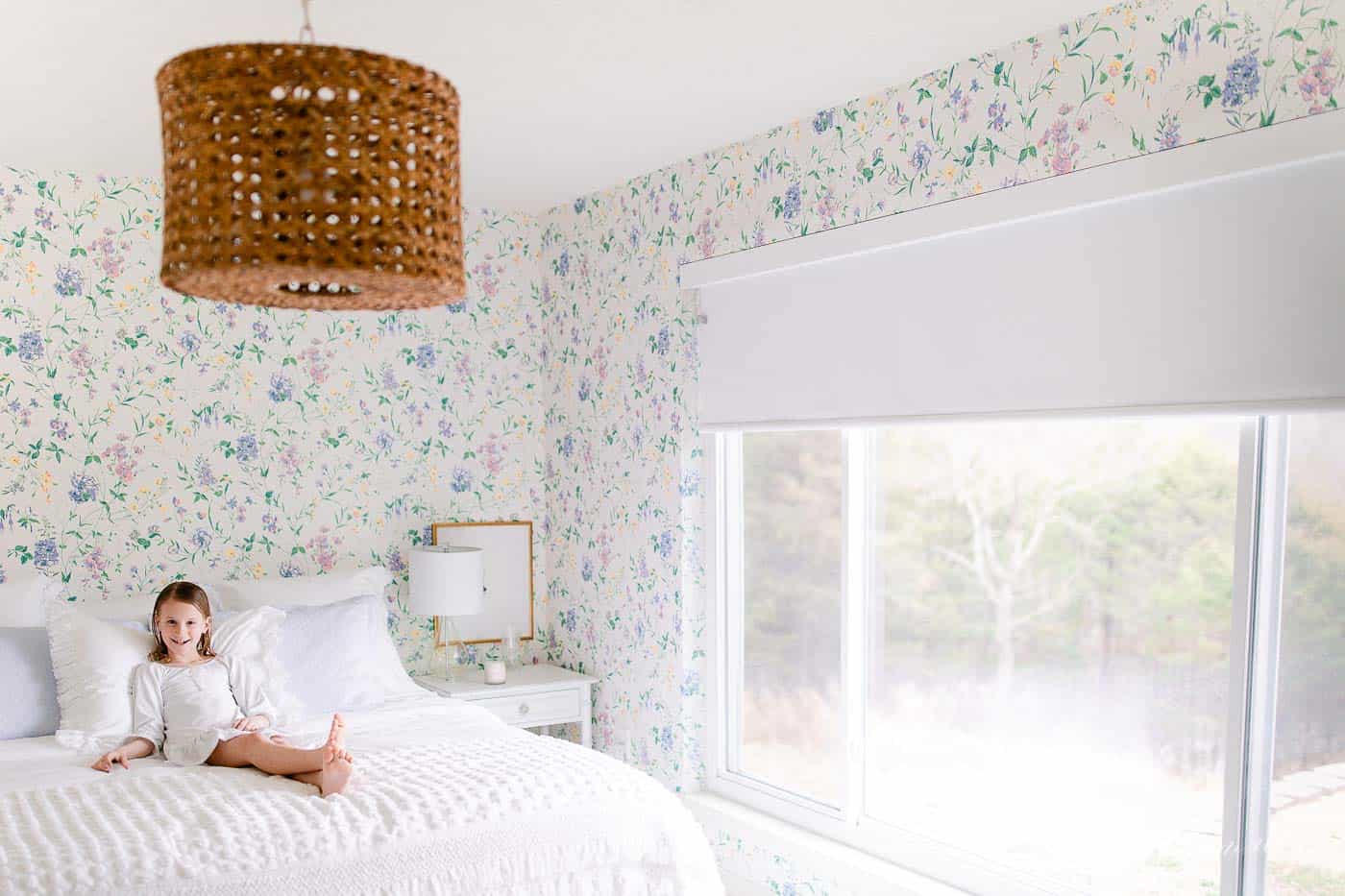 A white bedroom with wooden accents and a statement floral wallpaper. 