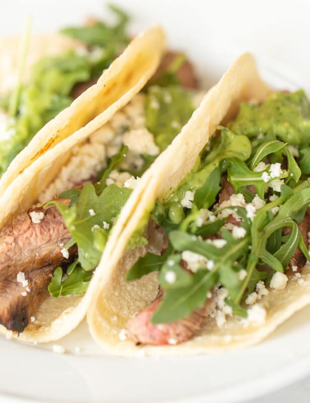 White plate with three small carne asada tacos.