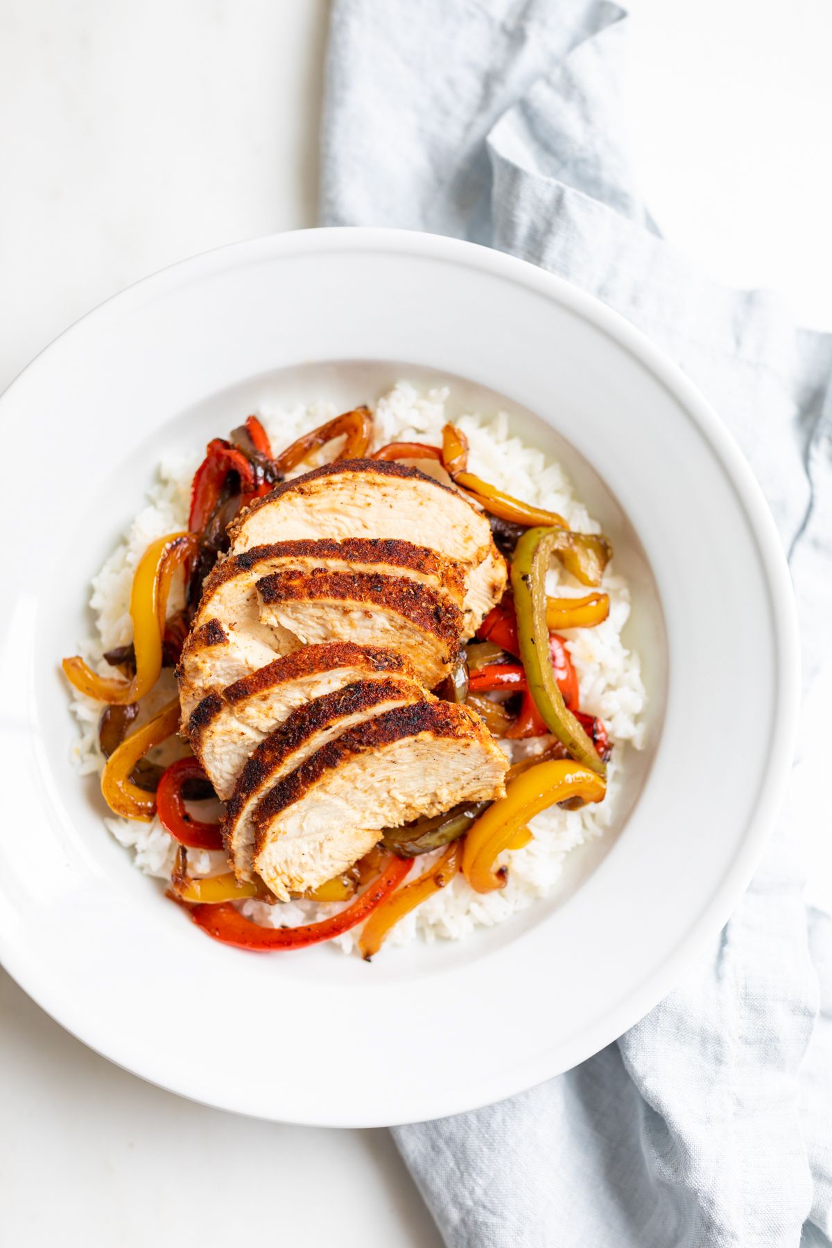 A chicken fajita bowl served over white rice and sauteed peppers.