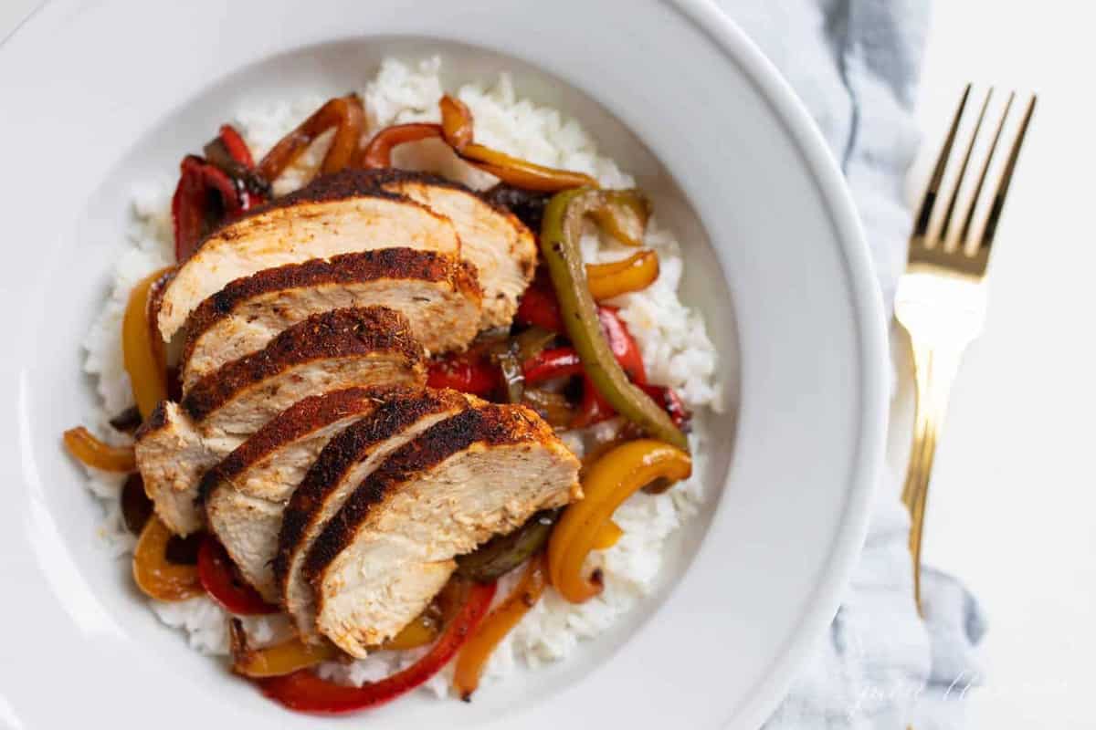 A bowl of chicken over rice, peppers layered in between.