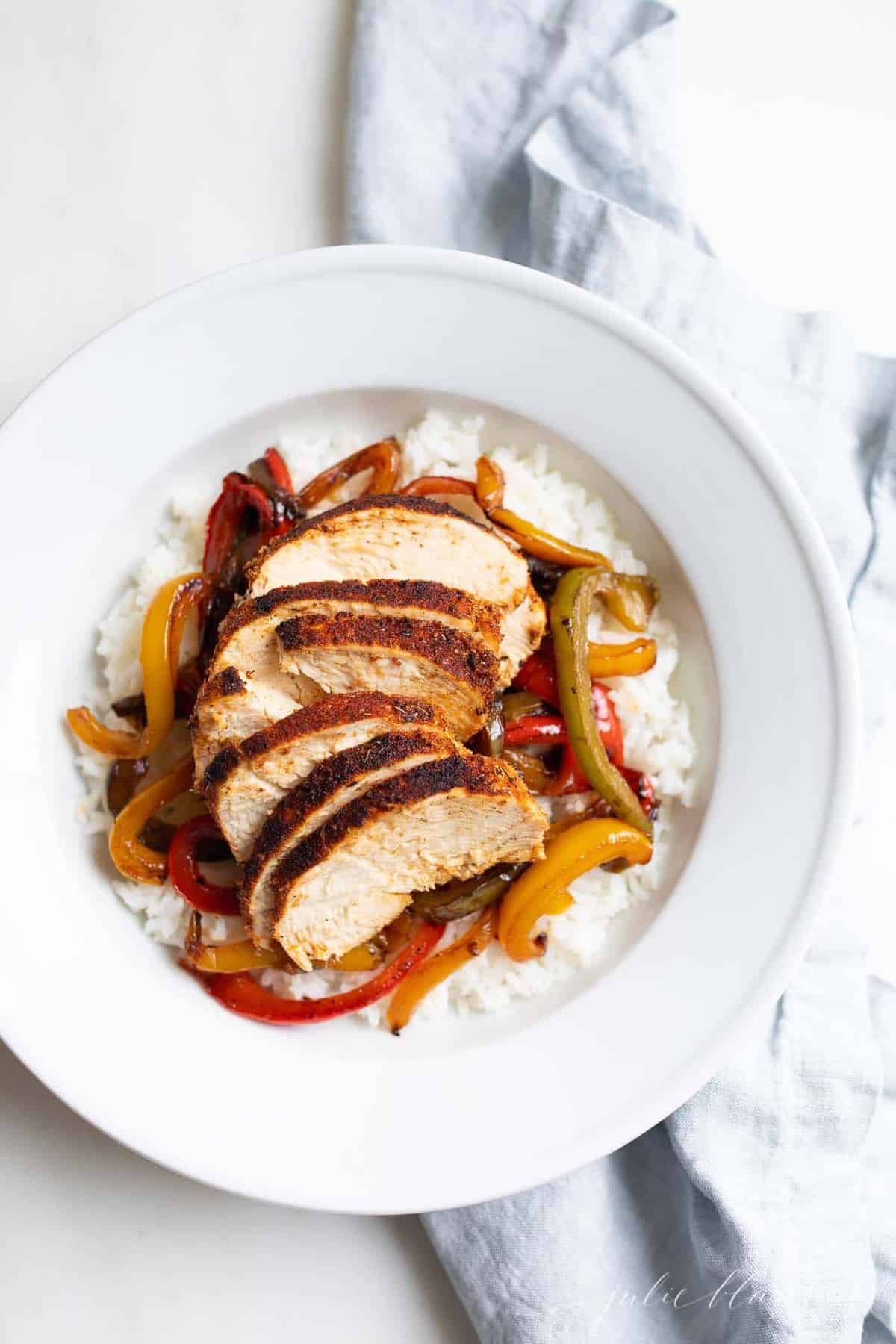 A bowl of chicken over rice, peppers layered in between.