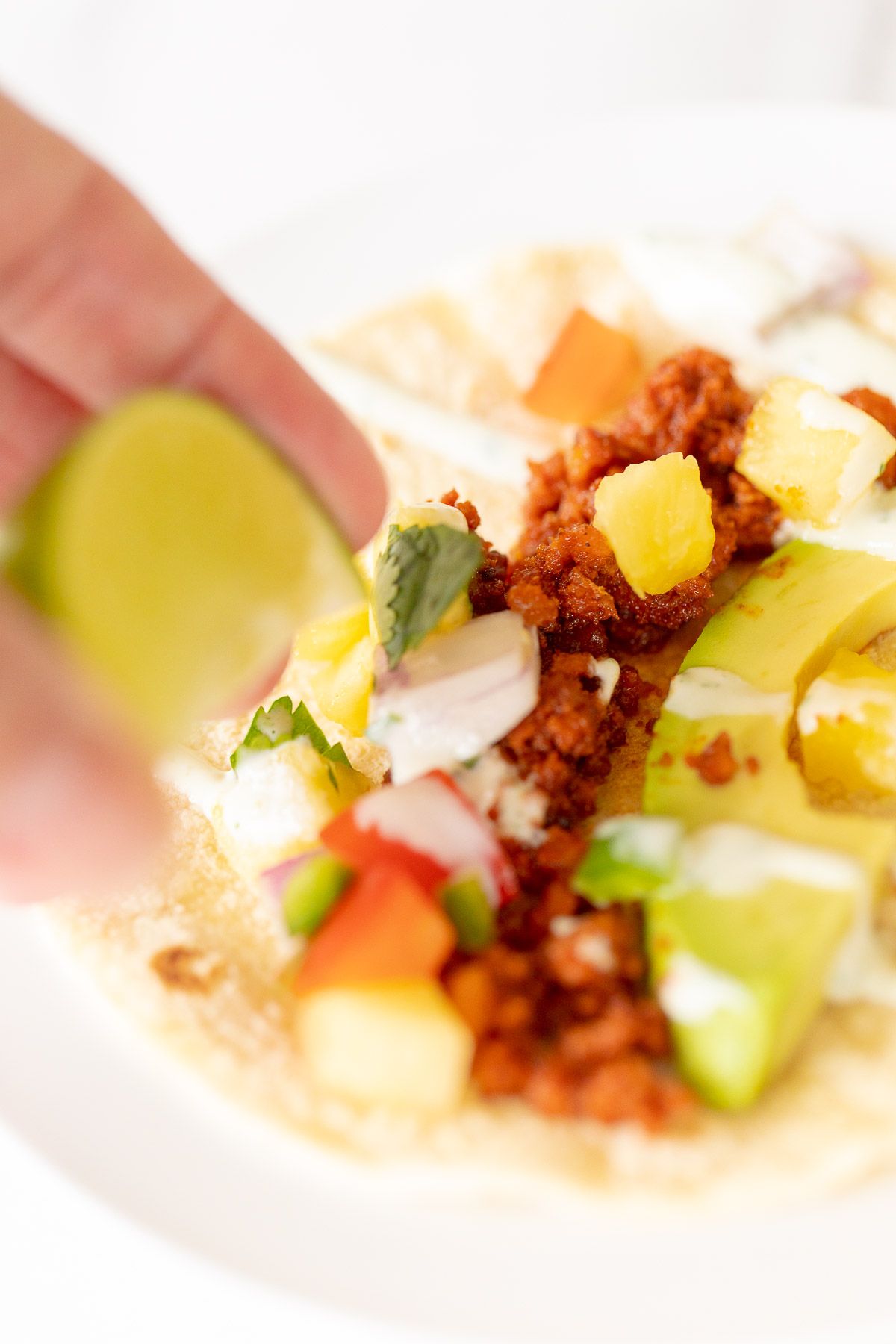A hand squeezing a sliced lime over a chorizo taco