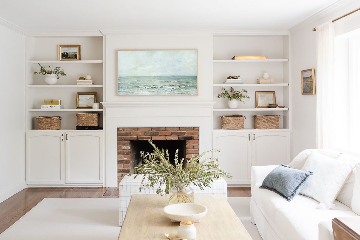 A living room with white furniture and walls and built ins painted in a cream paint color