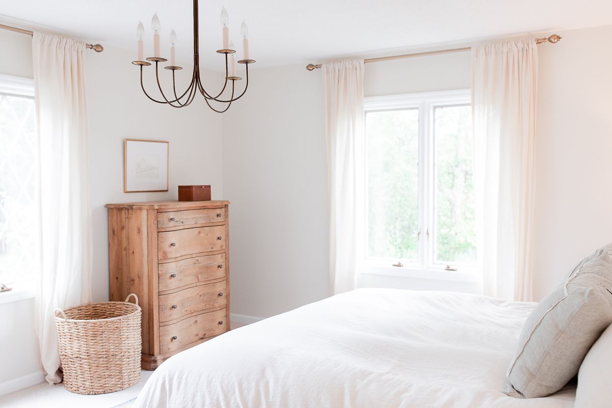 A primary bedroom with a wood dresser, with walls painted in a cream color paint.