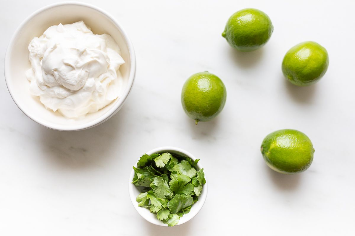 Ingredients for lime crema de cilantro laid out on a marble countertop.
