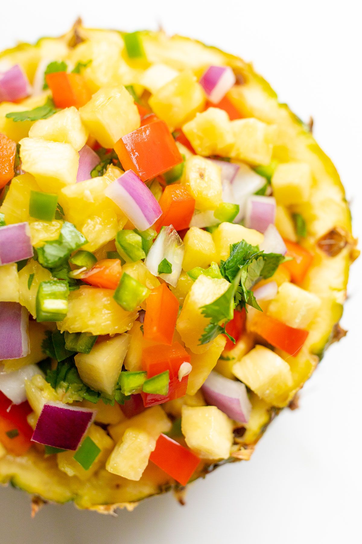 Pineapple salsa inside a pineapple bowl, on a white countertop.