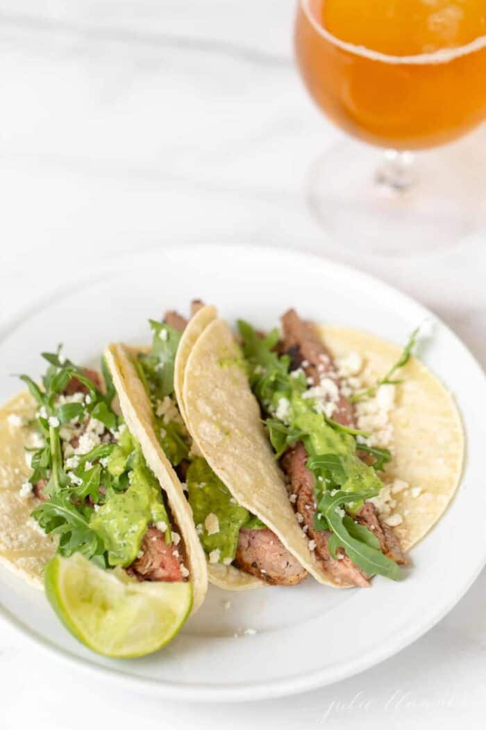 Carne asada tacos on a white plate.