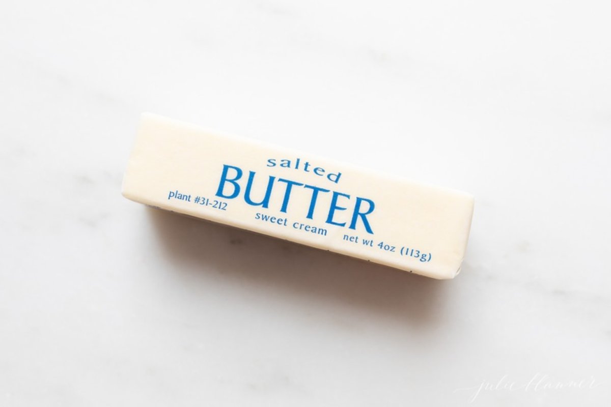 A single stick of salted butter on a marble countertop.