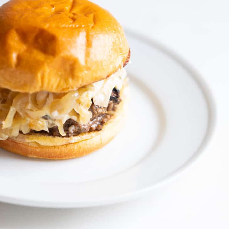 White surface, white place featuring a gourmet burger on a brioche bun.