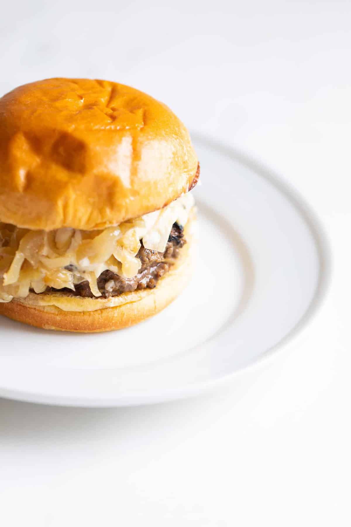 A gourmet burger on a white plate with a white background. 