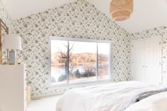 A white bedroom with wooden accents and a statement floral wallpaper. 