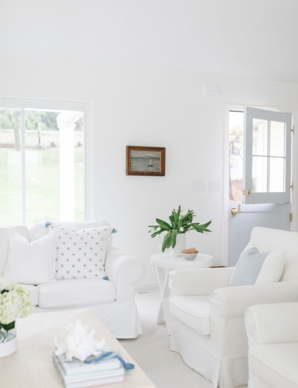 a white living room with white sofas and pillows in blue and white pillow covers