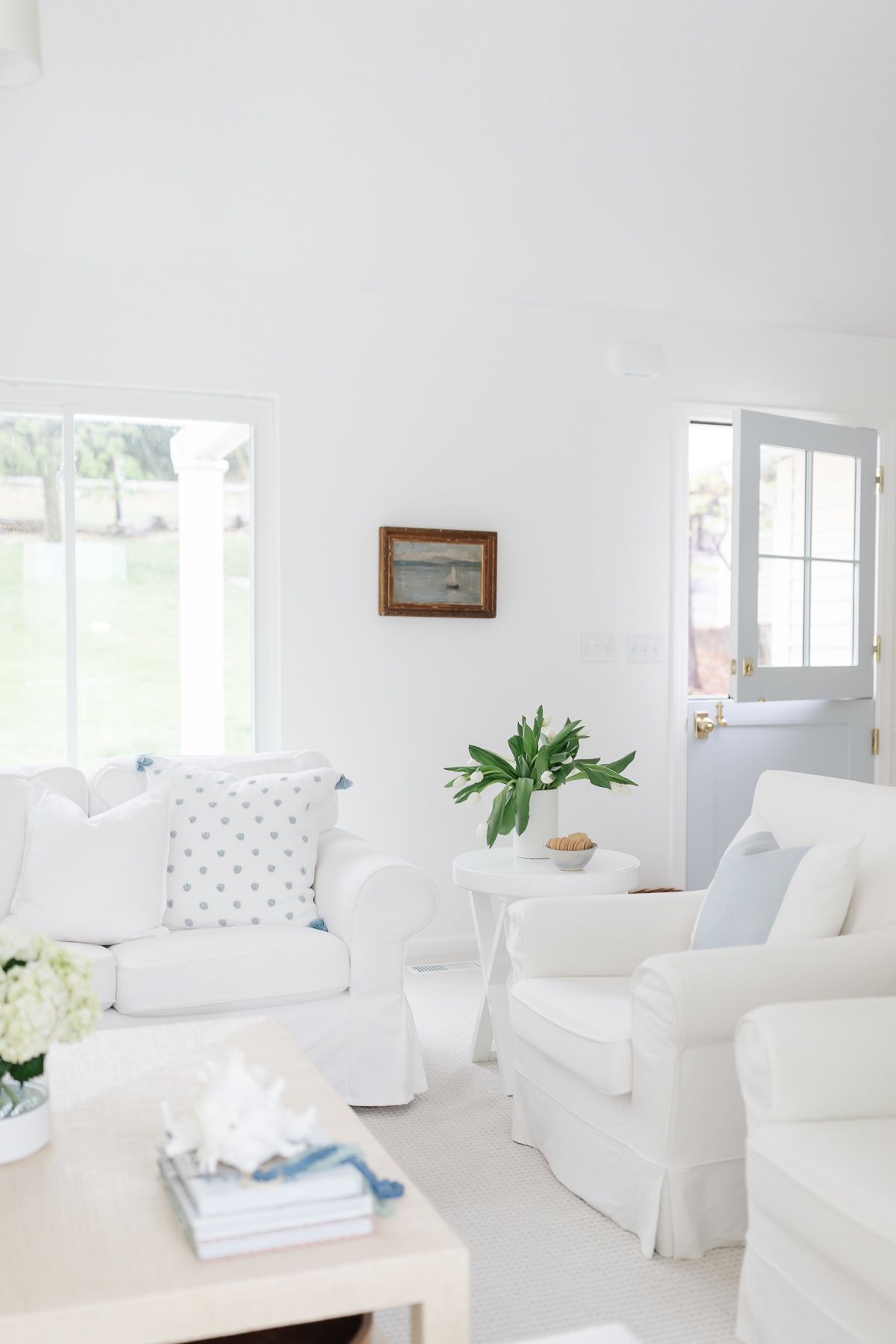 a white living room with white sofas and pillows in blue and white pillow covers