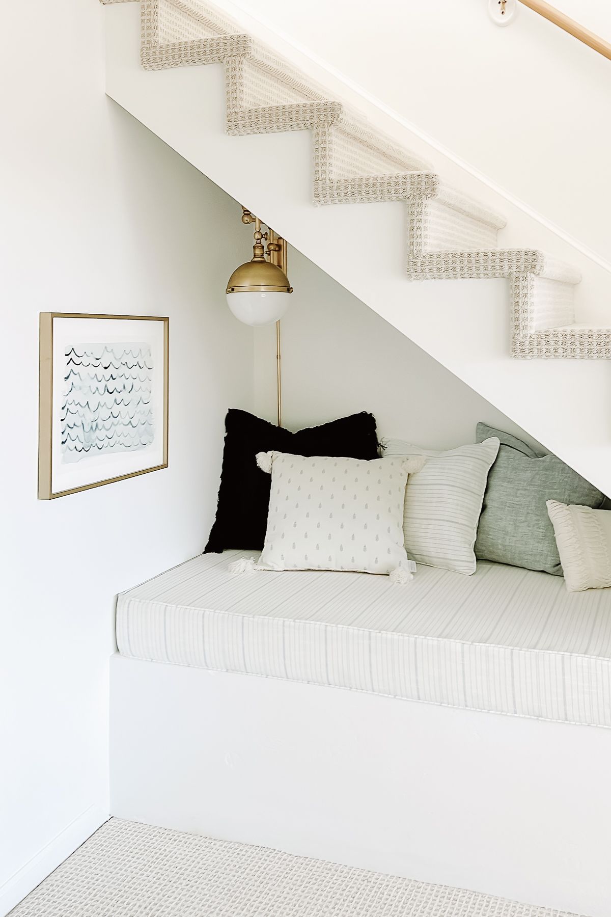 A nook under an open stair case decorated with blue and white pillow covers
