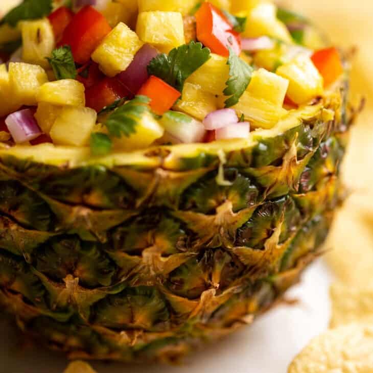 A fresh bowl made from a cut pineapple, filled with pineapple salsa.