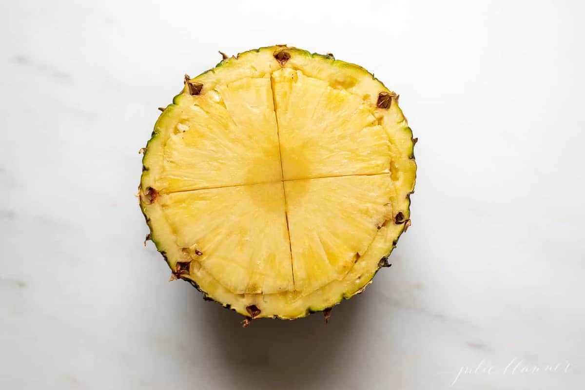 Marble surface with half a pineapple, scored across the middle.