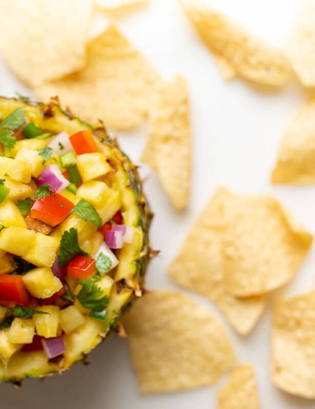 Corn salsa in a pineapple bowl, surrounded by tortilla chips.