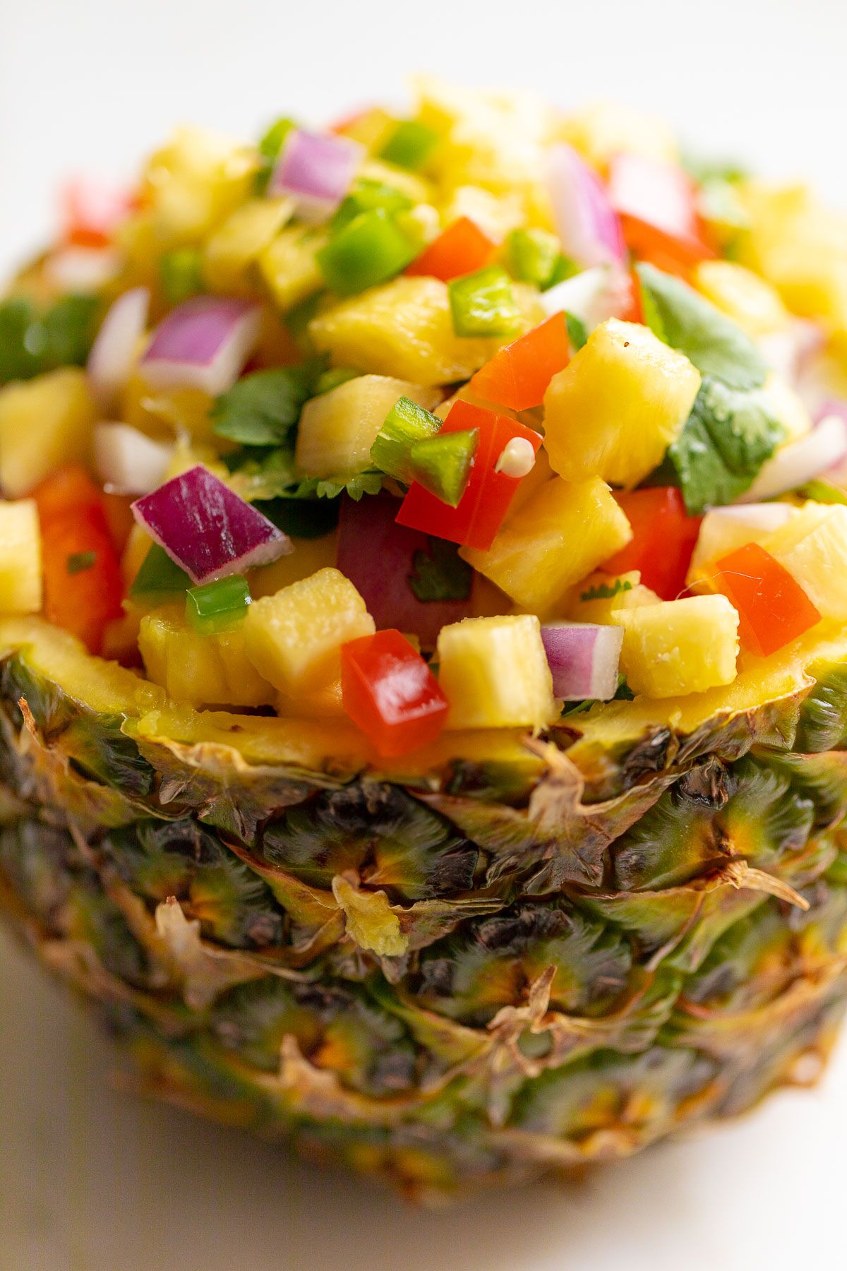 Pineapple salsa inside a pineapple bowl, on a white countertop.