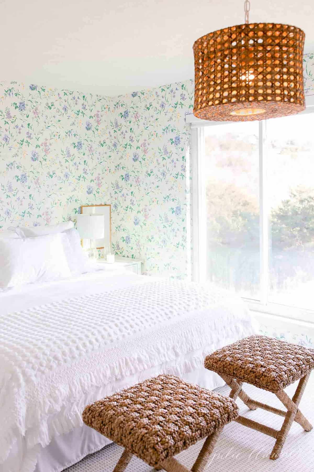 A white bedroom with wooden accents and a statement floral wallpaper. 