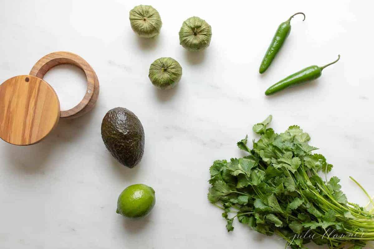 Ingredients for fresh serrano sauce laid out on a marble surface