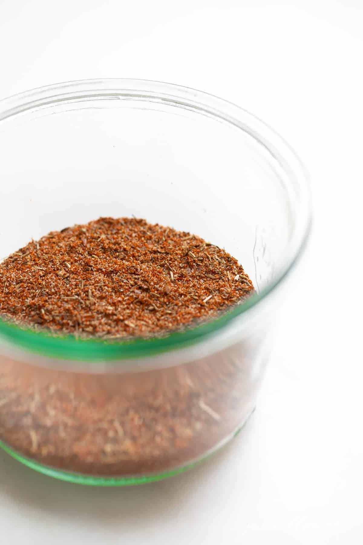 Blackened seasoning blend in a clear bowl on a white surface.