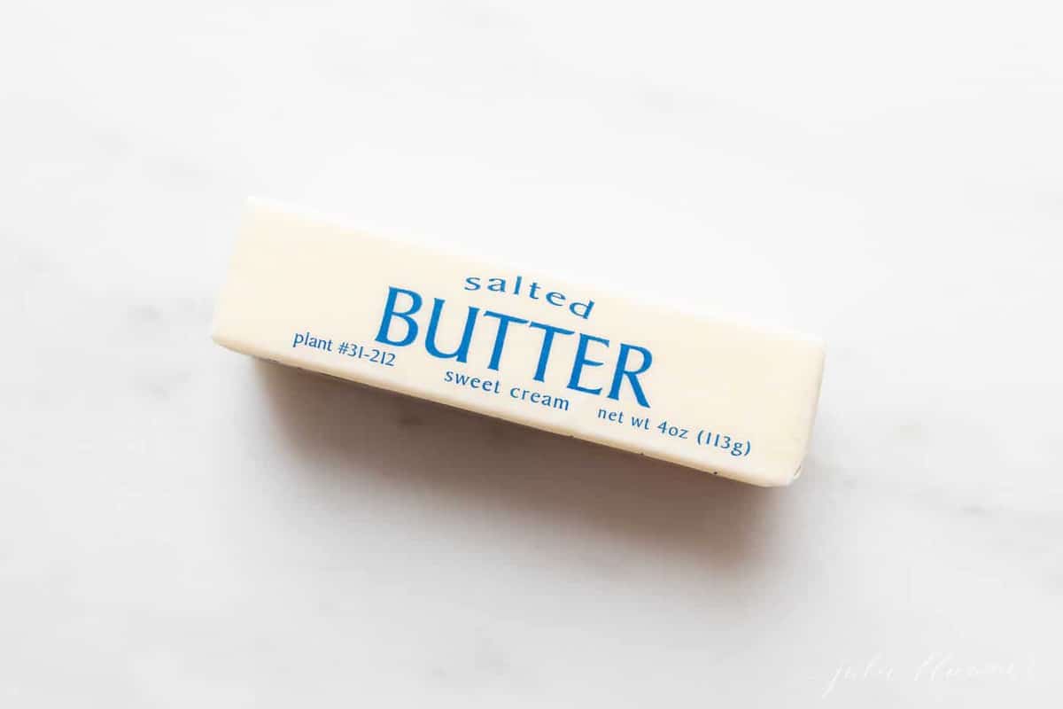 A stick of wrapped salted butter on a marble surface.