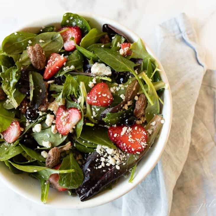 A white bowl full of a fresh spring mix salad.