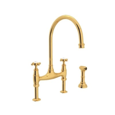 An unlacquered brass kitchen faucet against a white background.