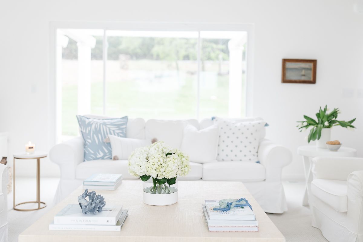 a white living room with white sofas and pillows in blue and white pillow covers