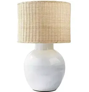 A table lamp with a round white ceramic base and a cylindrical woven rattan lampshade.