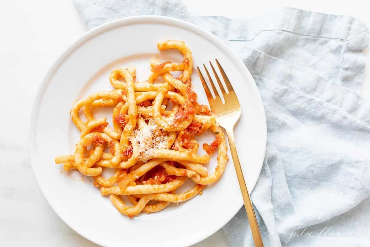 A white plate filled with homemade amatriciana pasta and sauce
