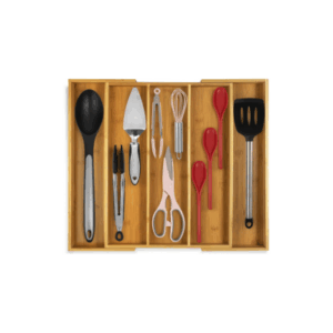 Wooden drawer organizer with built-in drawer dividers keeps assorted kitchen utensils—spoon, tongs, scissors, spatula, serving fork, whisk, and measuring spoons—neatly arranged inside.