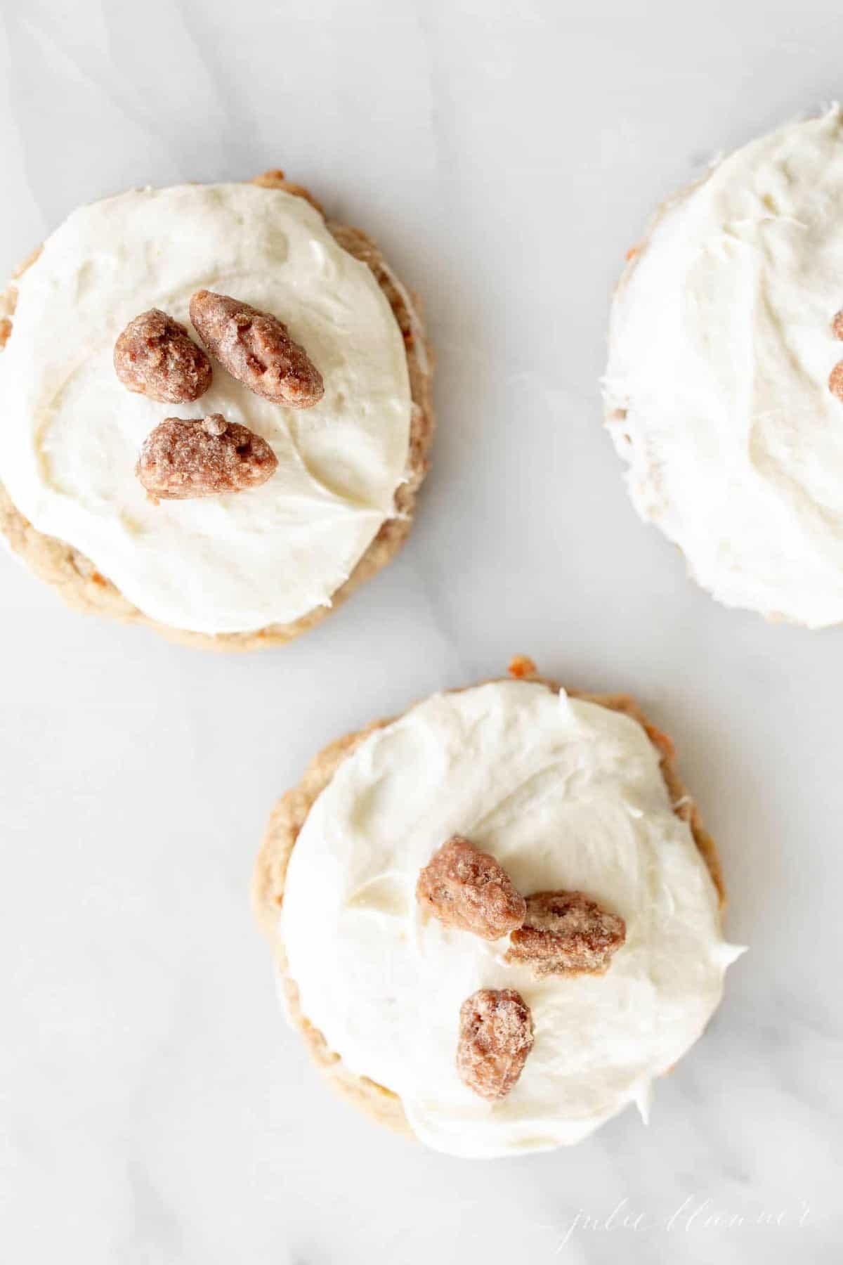 Cookies covered in white frosting, sugared pecans on top.