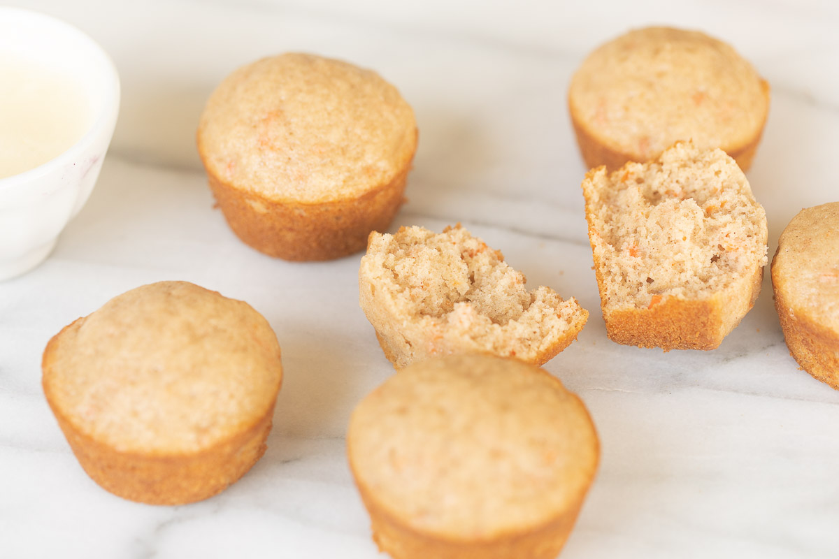 Carrot Cake Muffins on a marble table with a cup of milk.