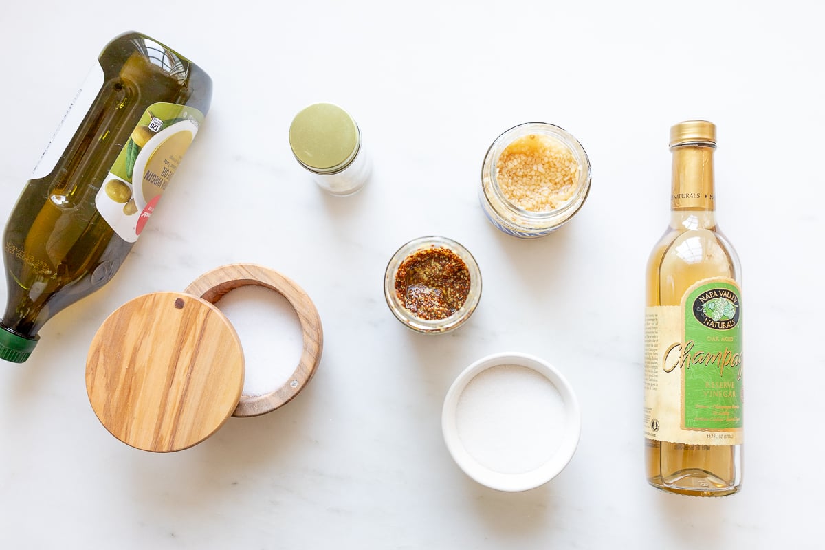 Ingredients for a champagne vinaigrette recipe laid out on a marble surface.