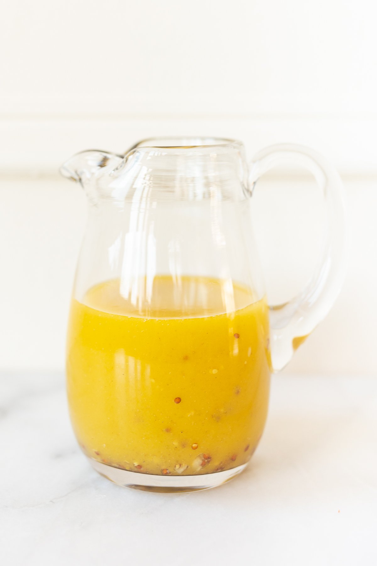 A pitcher of orange Champagne Vinaigrette sitting on a table.