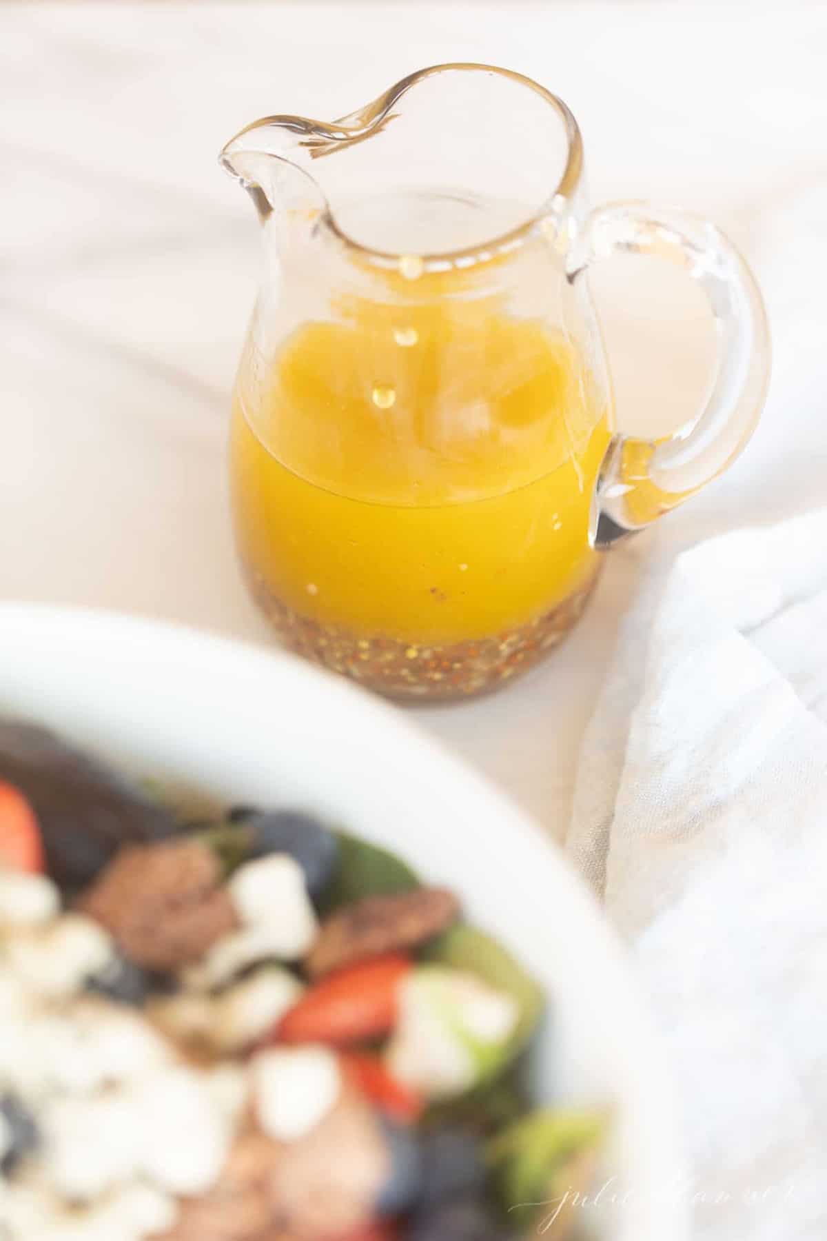 Vinaigrette in a glass pitcher on a marble surface. 