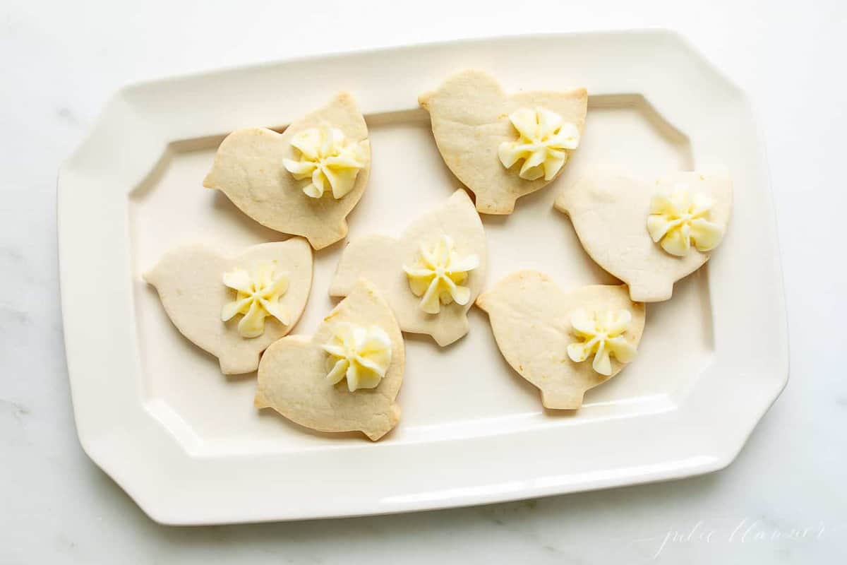 A white platter with lemon frosted cookies cutout as ducks.