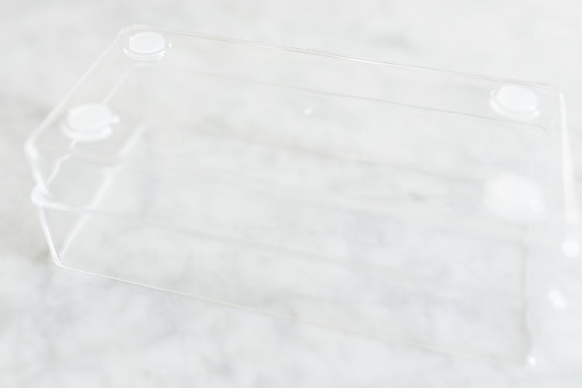 A clear plastic rectangular box with rounded corners, perfect as a drawer organizer, sits on a white marble surface.