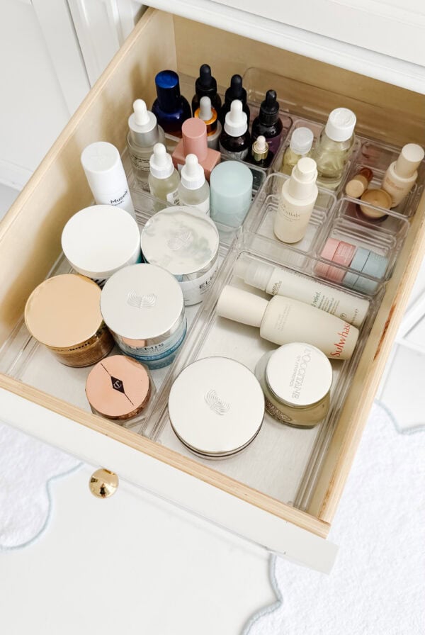 An organized drawer featuring various skincare and beauty productsโcreams, jars, dropper bottles, and tubesโall neatly arranged with clear plastic drawer organizers.