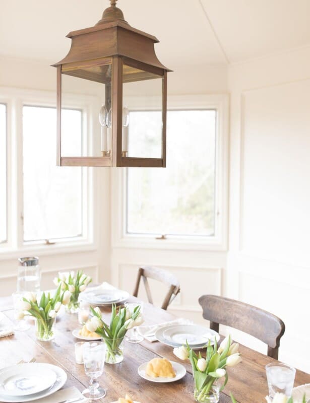 A white dining room with an Easter centerpiece of tulips in small vases