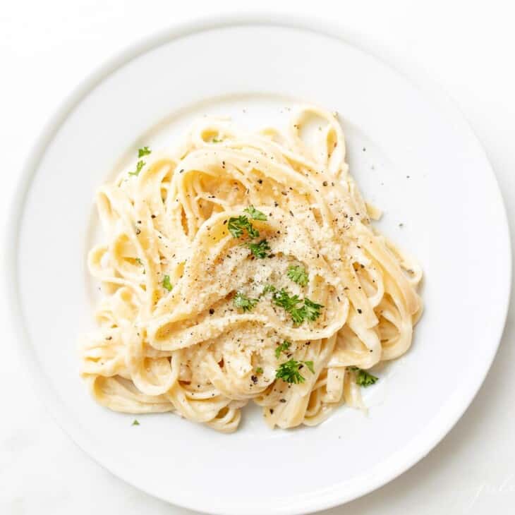 White plate full of fettuccine alfredo.